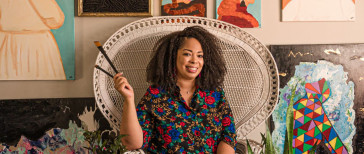 Artist sitting in chair with paint brushes