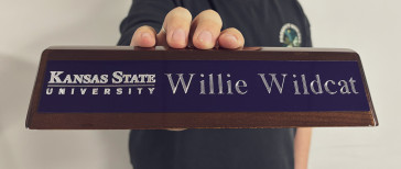 Walnut desk stand with a purple plaque being held my a hand