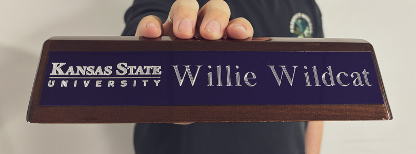 Walnut desk stand with a purple plaque being held my a hand