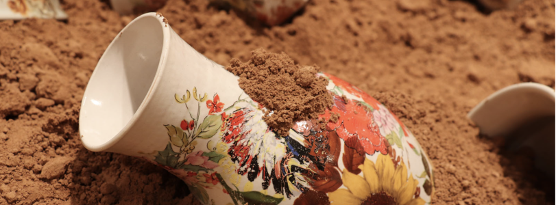 clay piece of art sitting in red sand