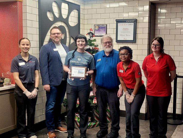 Miranda Jenne accepts her Employee Achievement Award with Executive Director Erik Kahl and other Chick-fil-A staff members