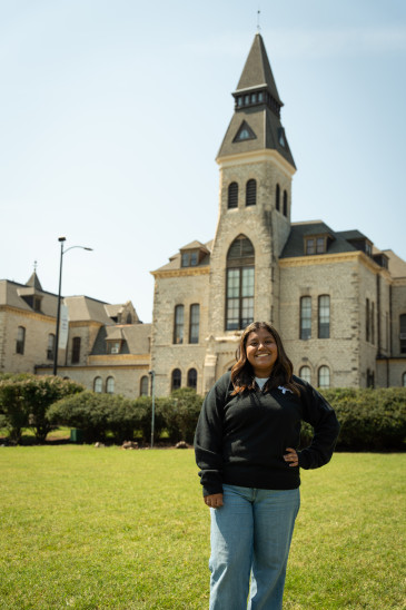 Laly Hernandez in a UPC jacket posed on Anderson Lawn with Anderson building in the backdrop