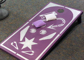 purple corn hole board with white and purple beanbags